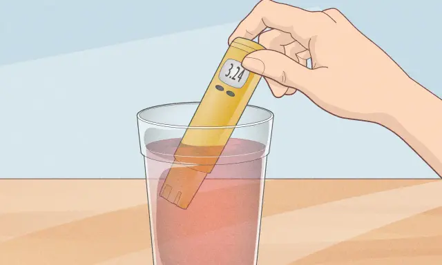 Une main tient un testeur de pH dans un verre d'eau. Le testeur affiche 3.24, indiquant que l'eau n'est pas à un pH neutre.