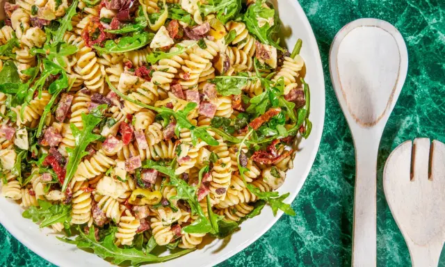 Pyszna sałatka z makaronem fusilli, rukolą, suszonymi pomidorami, oliwkami i kawałkami salami. Idealna na letnie dni.