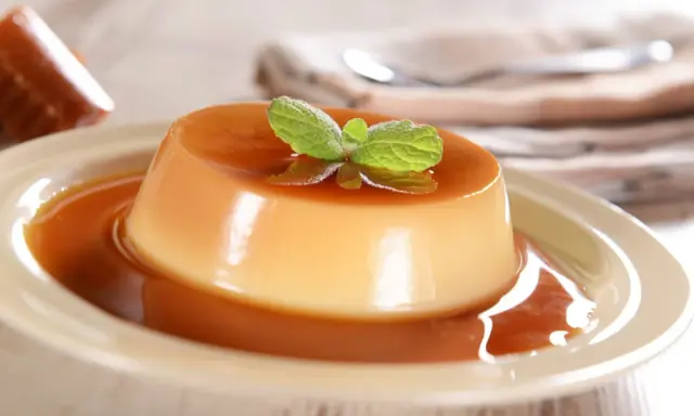Un délicieux panna cotta caramel, nappé de sauce et garni d'une feuille de menthe. Un dessert onctueux et gourmand.