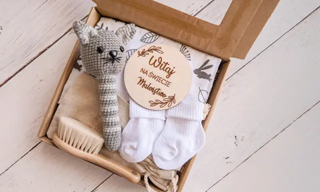 Zestaw na baby shower: szydełkowy kotek, skarpetki, szczotka i tabliczka "Witaj na świecie Maleństwo". Idealny pomysł, ile dać na baby shower.