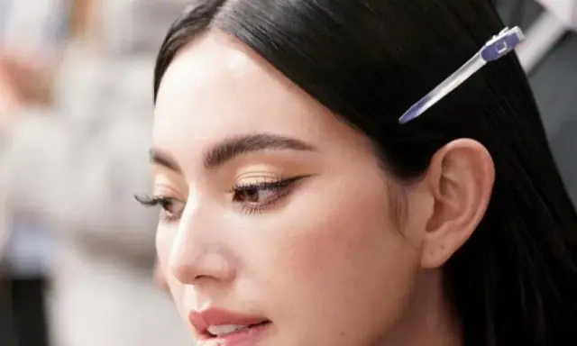 Primer plano de una mujer con ojos rasgados, delineado de gato y cabello oscuro recogido con una pinza.