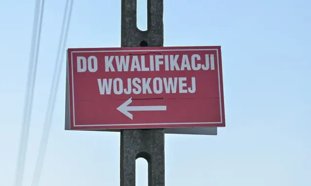 Czerwony znak z białym napisem "DO KWALIFIKACJI WOJSKOWEJ" i strzałką w lewo. Kategoria: d wojsko.
