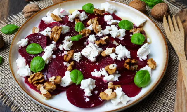 Ein Teller mit traditionellem Rote Bete Salat, garniert mit Feta, Walnüssen und Basilikum.