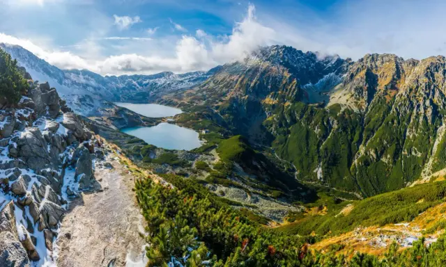 Widok na dwa górskie jeziora otoczone skalistymi szczytami i zielonymi zboczami. To jedne z tych **ciekawe miejsca w górach**, które zapierają dech w piersiach.