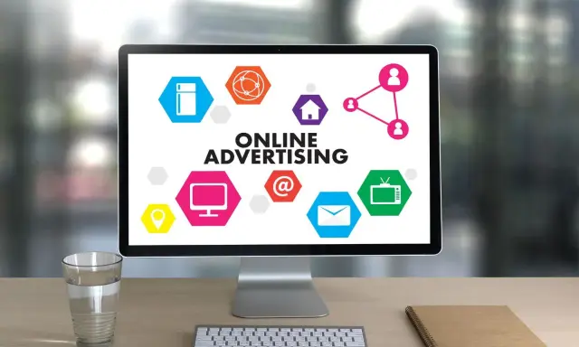 Komputer z hasłem "ONLINE ADVERTISING" i ikonami symbolizującymi różne formy reklamy online. Ciekawa reklama!
