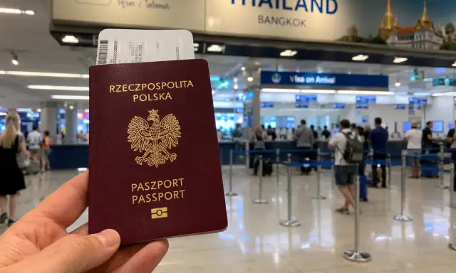 Polski paszport i bilet lotniczy w ręku, w tle tablica "THAILAND BANGKOK" i stanowiska "Visa on Arrival". Sprawdzanie tajlandia warunki wjazdu.