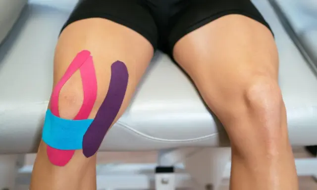 Kolano z kolorowym tapingiem, wspierającym więzadła poboczne.