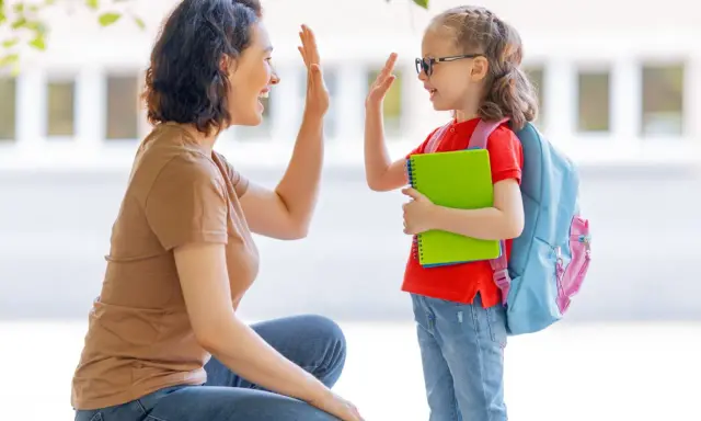 Madre y hija se dan un choque de manos, un momento de crianza positiva antes de ir a la escuela.