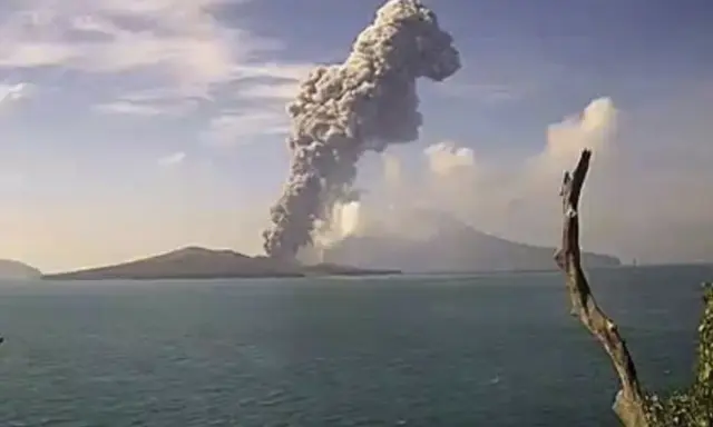 Potężna chmura dymu i popiołu wyrzuca w niebo wulkan Krakatau, tworząc dramatyczny widok nad spokojnym morzem.