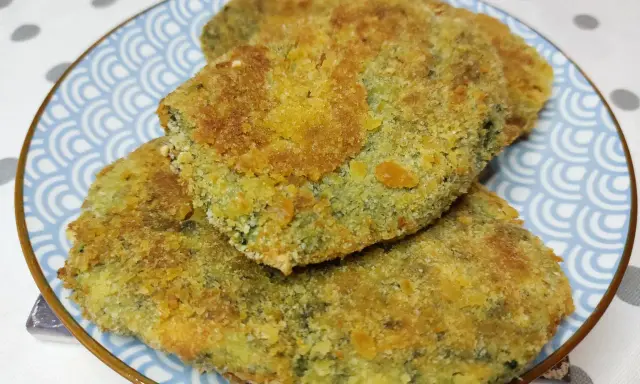 Tre spinacine fatte in casa, dorate e croccanti, servite su un piatto blu con decorazioni a onde.