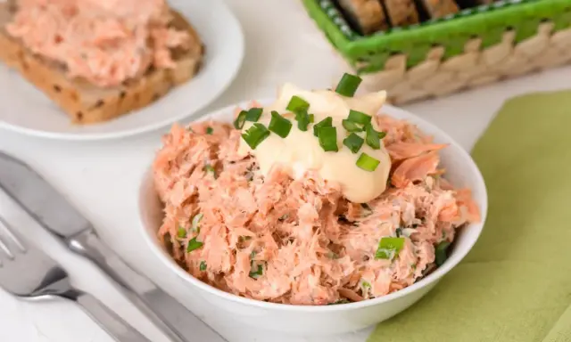 Pyszna pasta z pstrąga wędzonego, udekorowana majonezem i szczypiorkiem, gotowa do podania na chlebie.