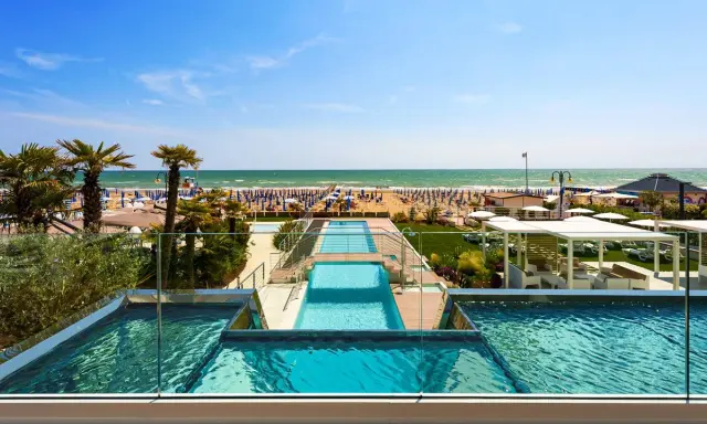 Lido di Jesolo atrakcje: baseny z widokiem na plażę, palmy i morze. Idealne miejsce na wakacje.