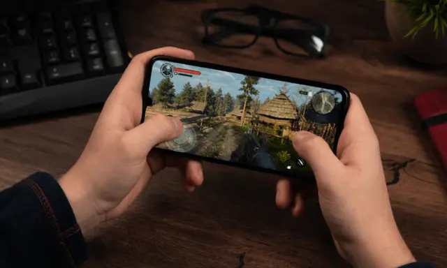 Ręce trzymają smartfon z grą akcji w stylu fantasy. To jedna z najlepszych gier mobilnych.