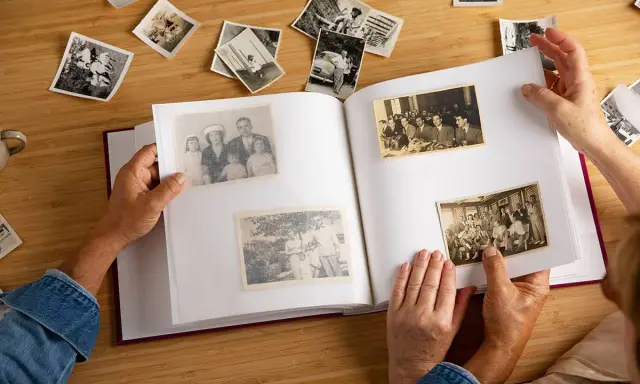 Manos hojeando un álbum de fotos antiguas, reviviendo recuerdos. Quizás buscando frases 50 aniversario para acompañar estas imágenes.