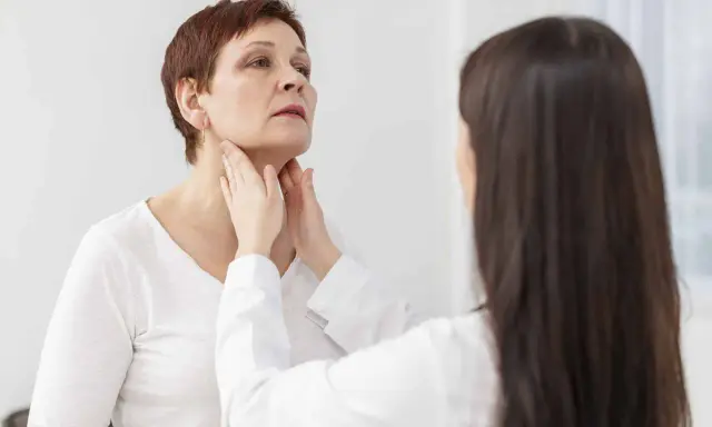 Medico esamina il collo di una paziente, possibile indicazione per una scintigrafia tiroidea.
