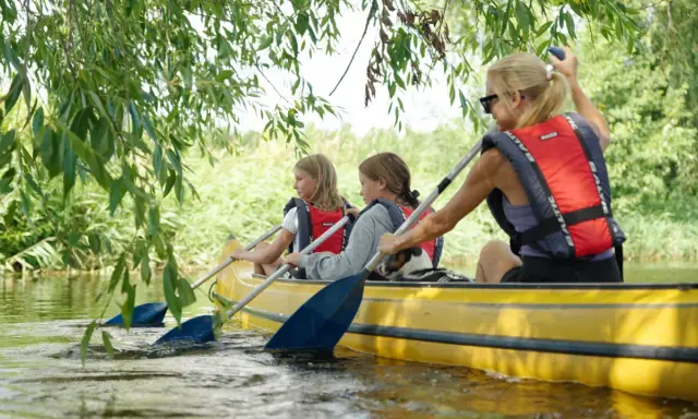 En familj njuter av att paddla kanot på en lugn vattendrag, kanske på Gotland.