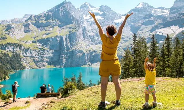 Familia disfrutando de un día en la suiza con niños, con un lago turquesa y montañas imponentes de fondo.