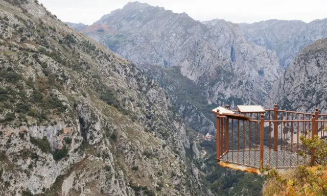 Mirador en la ruta del desfiladero de la Hermida, con imponentes montañas y un balcón de metal oxidado.