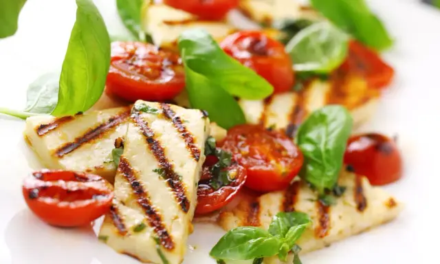 Grillowany serek halloumi z pomidorkami koktajlowymi i bazylią, apetyczna przekąska.
