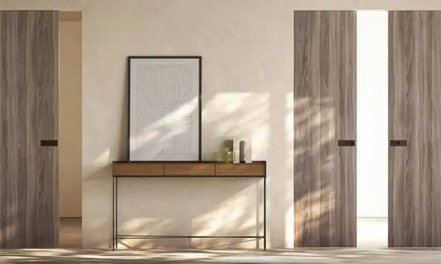 Porta in cartongesso con finitura in legno, minimalista e moderna, con un quadro astratto appeso sopra un tavolino.