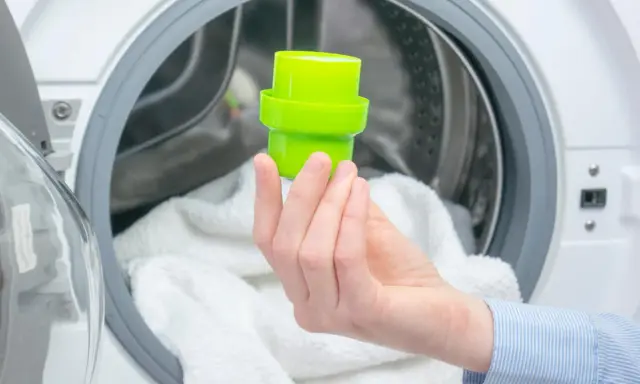 Grüne Kappe mit Waschmittel wird in die Waschmaschine gegeben.