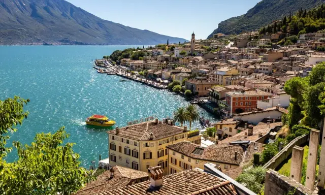 Limone sul Garda cosa vedere: pittoresca cittadina sul lago, con case colorate, un battello giallo e montagne sullo sfondo.