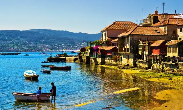 Un pueblo costero gallego, con barcas en el agua y casas de piedra, uno de los pueblos mas bonitos de Galicia.