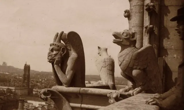 Kamienne gargulce Notre Dame spoglądają na Paryż. Jeden z nich, z rękami przy twarzy, wydaje się zamyślony.