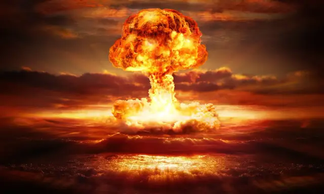 Potężny grzyb atomowy nad oceanem. Widoczne przerażające skutki bomby jądrowej: fala uderzeniowa, ogień i dym.