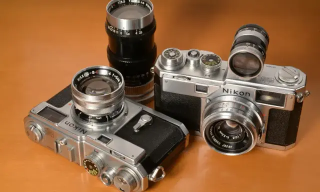 Kolekcja aparatów Nikon z obiektywami. Dwa modele Nikon z lat 50. i 60. XX wieku, każdy z innym obiektywem Nikkor.