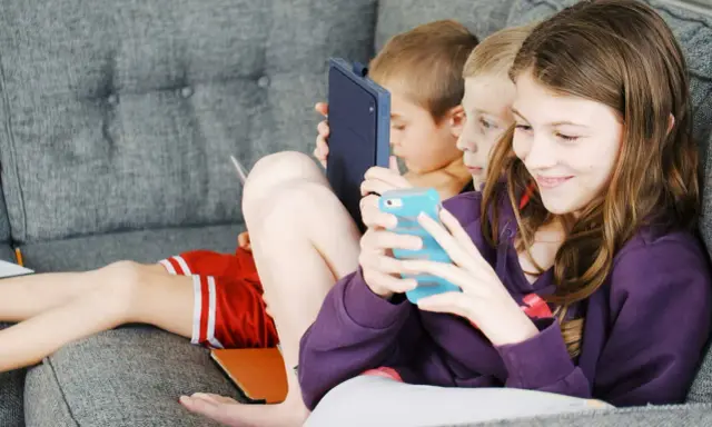 Trois enfants absorbés par leurs écrans, un rappel pour un atelier sensibilisation aux écrans.