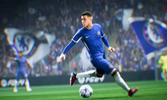 Piłkarz w niebieskiej koszulce Chelsea drybluje piłką na boisku, gotowy do strzału w grze FIFA 2k.