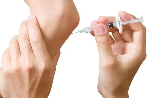 Eine Spritze wird an einem Ellbogen angesetzt. Dies ist ein Schritt in der biologika therapie zur Behandlung von Entzündungen.