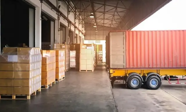 Almacén con camión y contenedores listos para la normativa de carga y descarga de camiones.