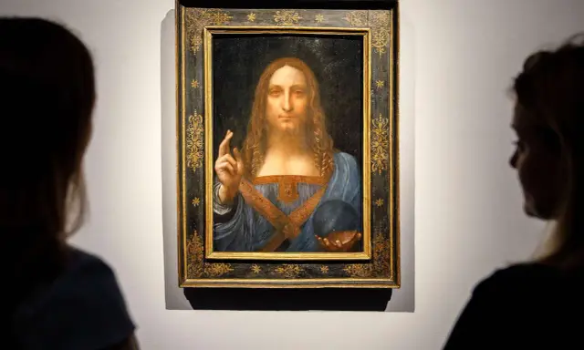 Two viewers admire Leonardo da Vinci's "Salvator Mundi," the most expensive piece of art ever sold, in its ornate frame.