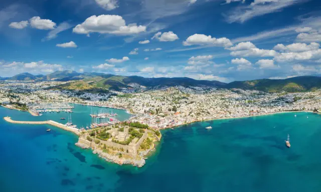 Widok na zamek i zatokę pełną łodzi. Czy to Bodrum, czy Alanya? Piękne turkusowe morze i białe domy na wzgórzach.