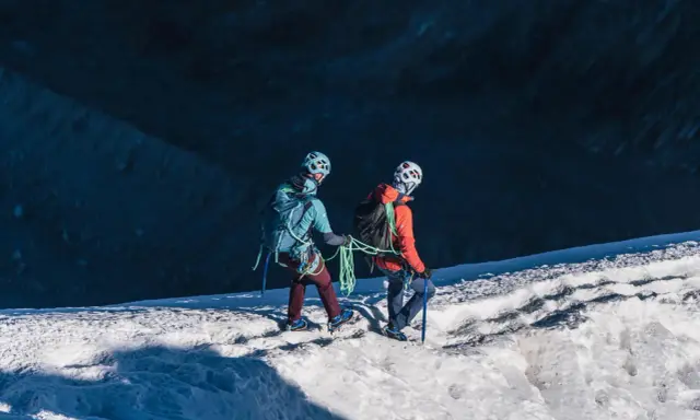 Dwóch alpinistów z raki i czekanami na lodowcu, przygotowuje się do wspinaczki.