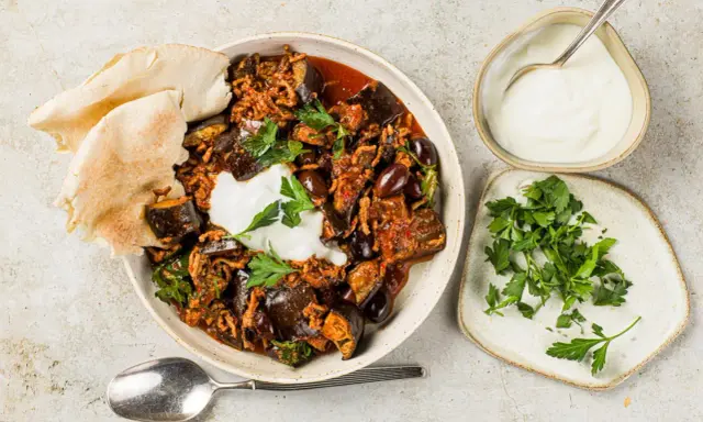 Délicieuse recette aubergine viande hachée, servie avec du pain pita, une cuillère de yaourt et du persil frais.