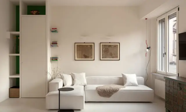 Soggiorno moderno: divano bianco, quadri antichi e libreria a giorno. Idee su come arredare con stile e funzionalità.