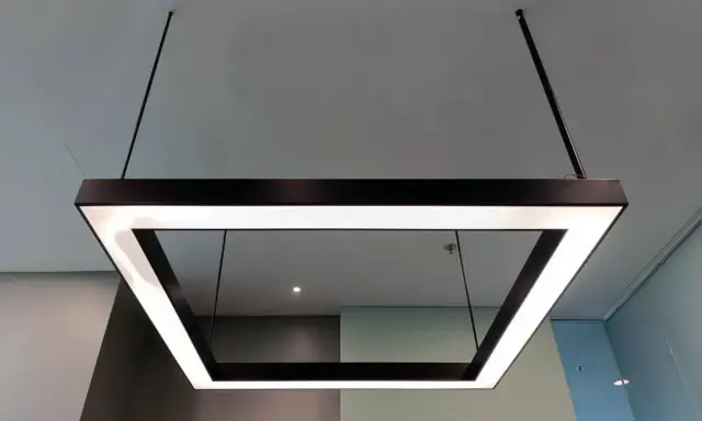 Nowoczesna podsufitka led w kształcie kwadratu, zawieszona na cienkich linkach, tworzy minimalistyczną i elegancką przestrzeń.