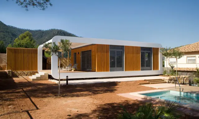 Une maison écologique moderne en bois avec une piscine et une vue sur les montagnes.