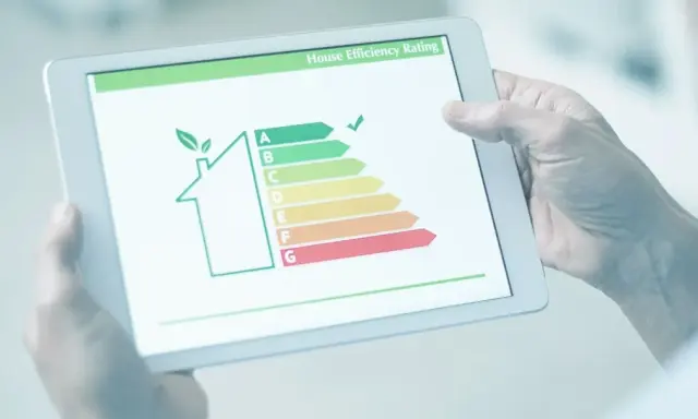 Persona revisa en tablet la validez del certificado energético de una casa, mostrando una escala de eficiencia.