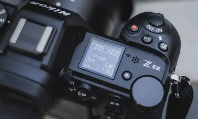 Górna część aparatu Nikon Z6 III z widocznym ekranem LCD, pokrętłem trybów i przyciskiem nagrywania.