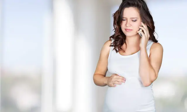 Gravid kvinna med orolig min ringer om sina Braxton Hicks sammandragningar.