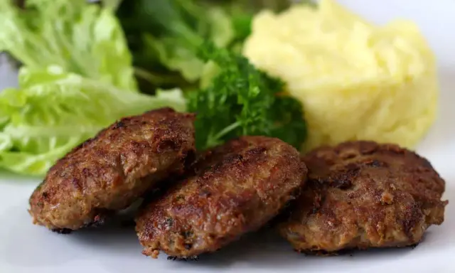 Drei gebratene Fleischpflanzerl mit Kartoffelbrei und Salat. Ein leckeres Fleischpflanzerl Rezept für zu Hause.