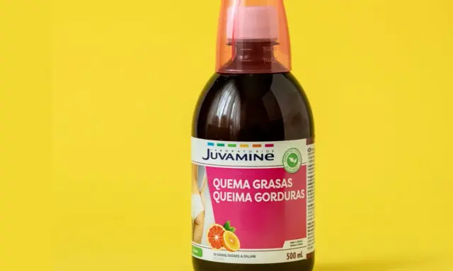 Botella de líquido quemagrasas con etiqueta rosa y naranja sobre fondo amarillo.