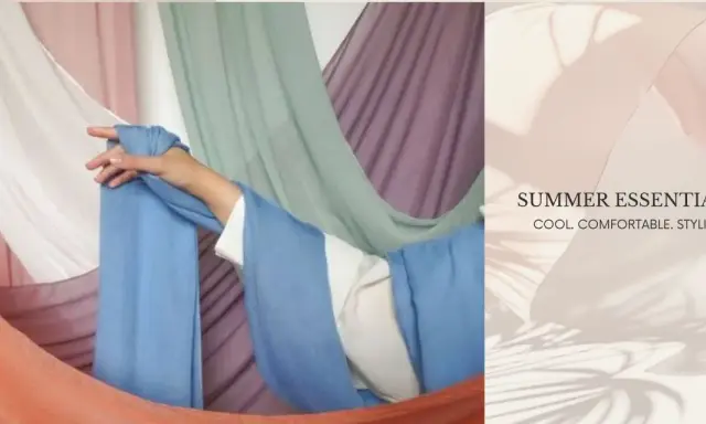 A hand drapes light blue fabric, suggesting the best clothing material for summer is breathable and cool.