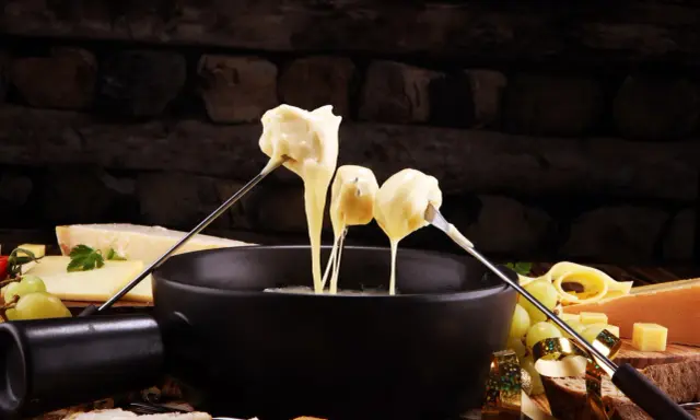 Fondue au fromage, une des spécialités culinaires parisiennes, servie avec du pain et des raisins.