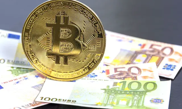 Moneda de Bitcoin sobre billetes de euro. El futuro del euro digital podría ser así.