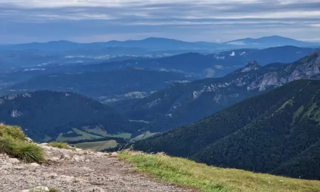 Kamienista ścieżka prowadzi przez zielone zbocza w kierunku malowniczych gór Mała Fatra.